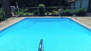 A rectangular swimming pool with clear blue water, surrounded by a tiled deck. - Charming 2BR Guest House w/ Pool - Perfect Getaway (West Tisbury)