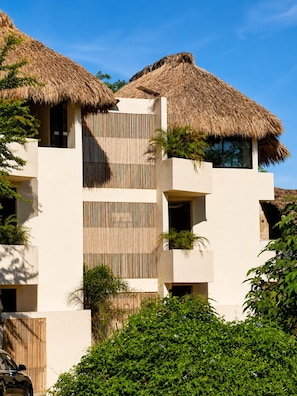 A modern building with multiple balconies, thatched roofs, and lush greenery. - Modern Flat in Zicatela • 100m from the Beach (Oax.)