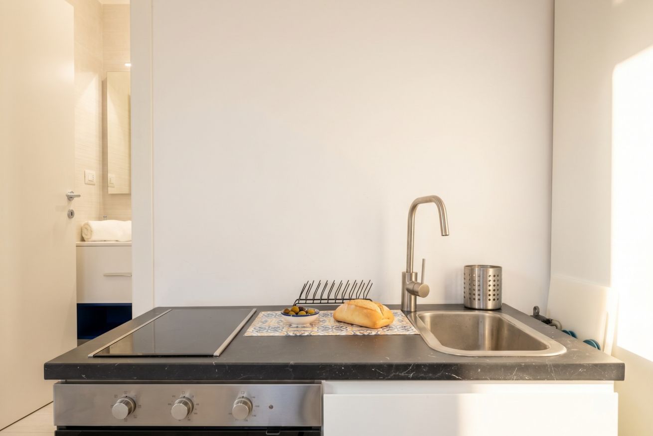 Une cuisine équipée d’une cuisinière à gaz, d’un évier et d’un petit plan de travail.