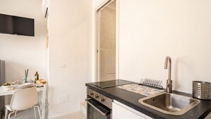 A modern kitchen with a black countertop, stainless steel sink, and a built-in oven. - SPA and Relax 2 - Elegant Seaside Studio (Monopoli)