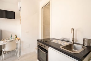 A modern kitchen with a black countertop, stainless steel sink, and a built-in oven. - SPA and Relax 2 - Elegant Seaside Studio (Monopoli)