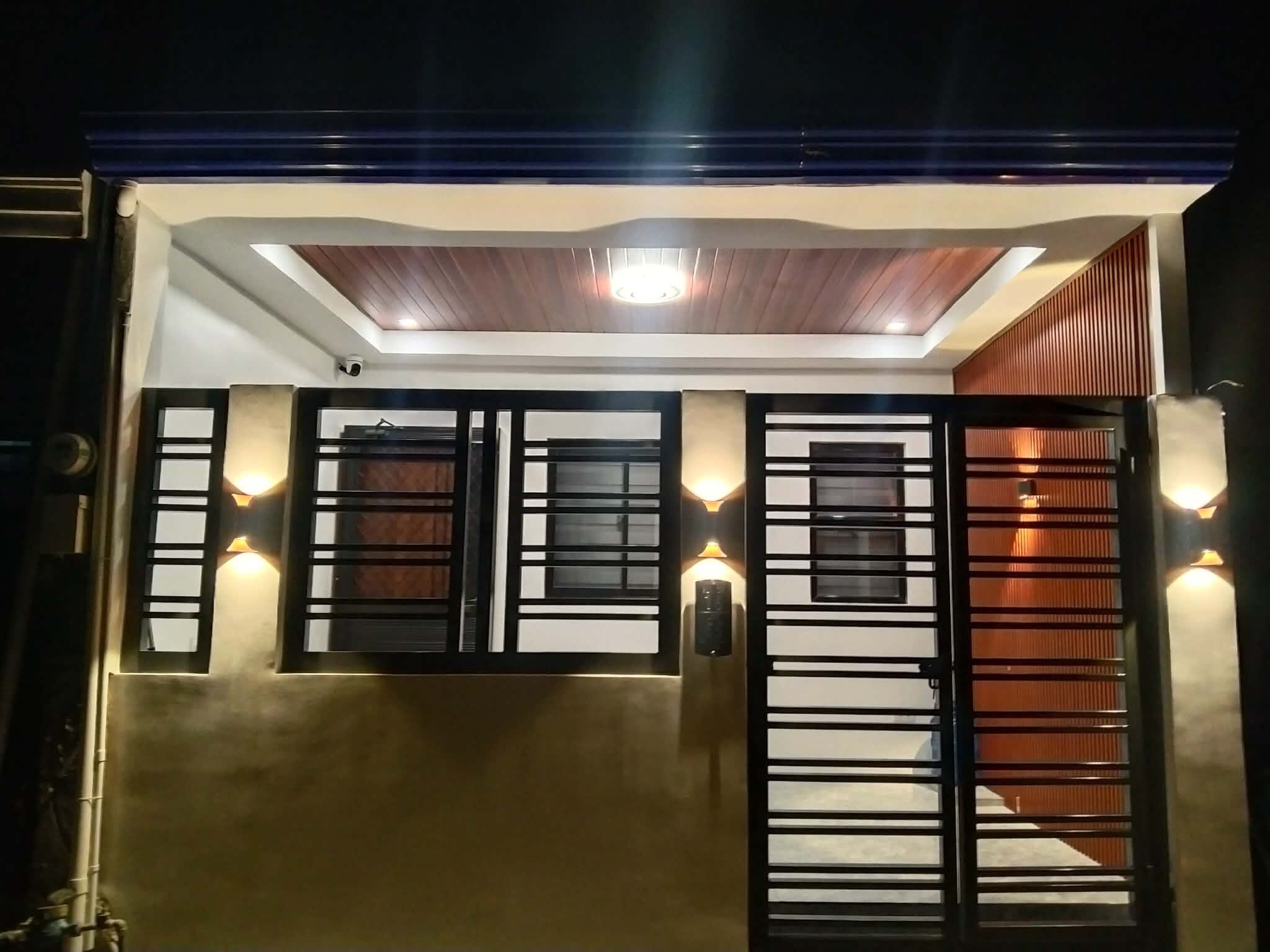 A modern building with a gated entrance, a security camera, and a recessed ceiling light.