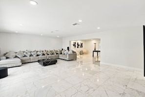 A spacious living area with a sectional sofa, a coffee table, and a minimalist design. - McCarty Mansion - Fort Pierce Waterfront Paradise - 7Br/6Ba - Sleeps 20 (Fort Pierce)
