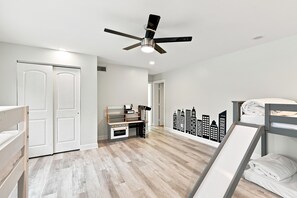 A room with a ceiling fan, a desk with a computer, a bed with a white mattress, and a cityscape wall decal. - McCarty Mansion - Fort Pierce Waterfront Paradise - 7Br/6Ba - Sleeps 20 (Fort Pierce)