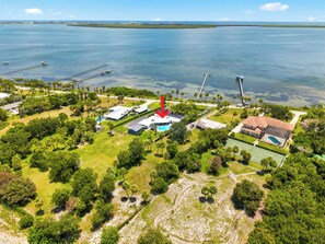 Vista aèria d'una propietat costanera amb piscina, pista de tennis i moll que s'endinsa a l'aigua.