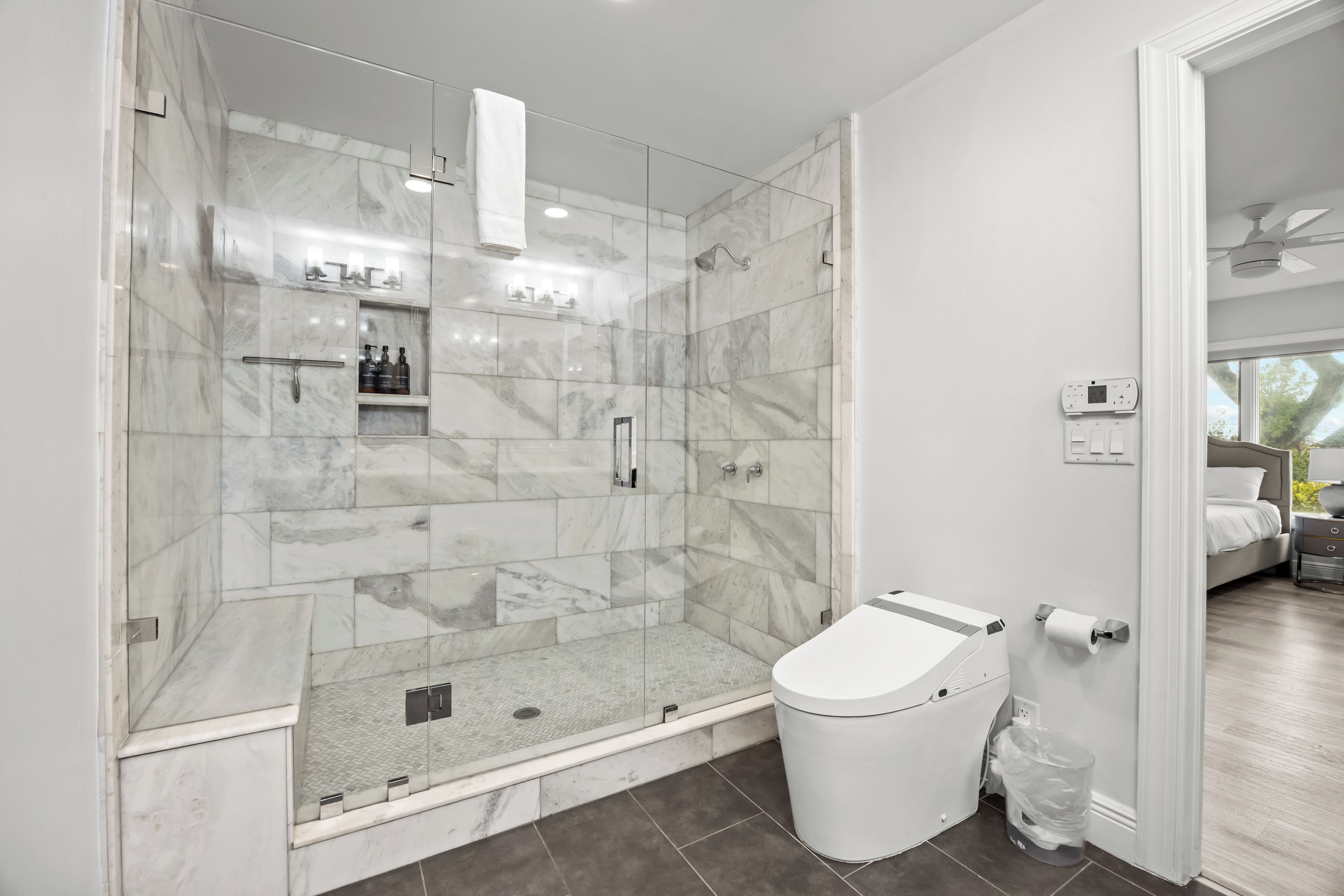 A modern bathroom with a glass-enclosed shower, a toilet, and a sink.