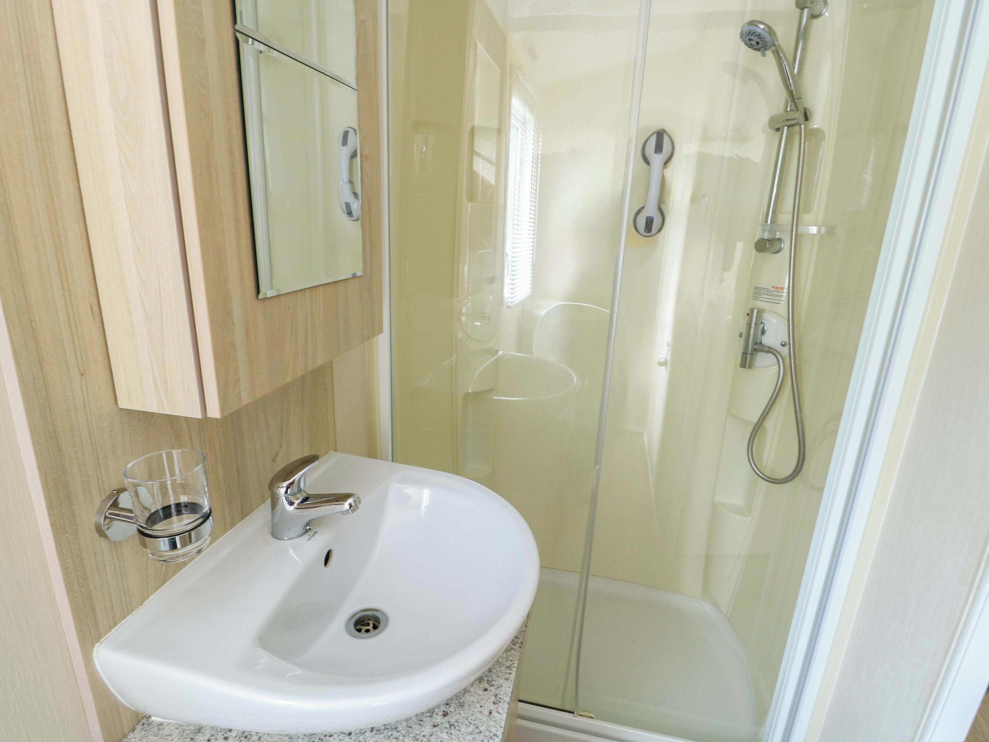 A bathroom with a white sink, a glass shower enclosure, and a mirror above the sink.