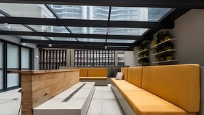 A modern interior with a skylight, a wooden bench, a yellow sofa, and a plant shelf. - Uwin 403 - Apartment 10 minutes from Chucri Zaidan (São Paulo)