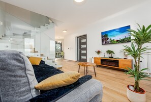 A modern living room with a sofa, a coffee table, a TV, a staircase, and a potted plant. - Seaview Villa Mar with pool, jacuzzi and sauna (Privlaka)