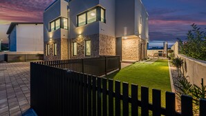 Uma casa moderna de dois andares, com um gramado bem cuidado e cerca de madeira.
