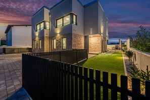 A modern two-story house with a well-maintained lawn and a wooden fence. - Seaview Villa Mar with pool, jacuzzi and sauna (Privlaka)