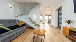 Uma sala de estar moderna com um sofá, uma mesa de centro de madeira, uma escada e uma lareira.