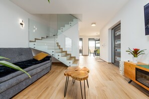 A modern living room with a sofa, a wooden coffee table, a staircase, and a fireplace. - Seaview Villa Mar with pool, jacuzzi and sauna (Privlaka)