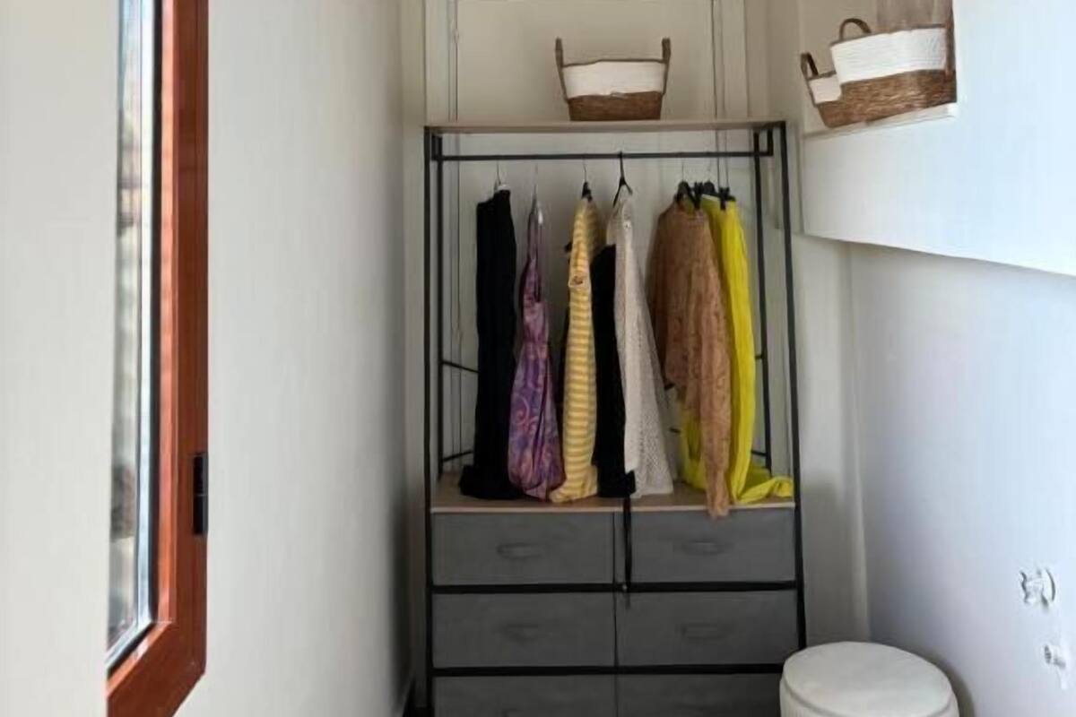 A hallway with a wardrobe, a hanging light fixture, and a window.