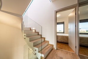 A modern staircase with glass railings leading to a bedroom with a large window. - Seaview Villa Sal with pool, jacuzzi and sauna (Privlaka)