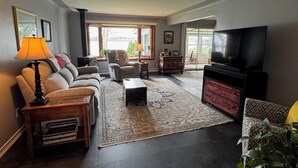 A living room with a sofa, armchairs, a coffee table, a TV, and a fireplace. - Just Peachy! Enjoy your private lake front home. (West Branch)
