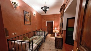 A narrow hallway with a bed, a door, and a small table with a lamp. - Riad La Maison Nomade (Marrakech)
