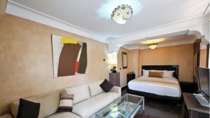 A hotel room with a sofa, a glass coffee table, a bed, and a television. - Riad La Maison Nomade (Marrakech)