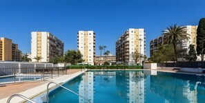 Ein Wohnhauskomplex mit Schwimmbad, mehreren Balkonen und umliegender Bepflanzung.