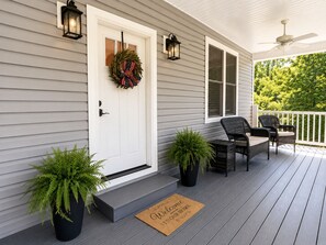 A porch with a white door, two potted plants, a welcome mat, and two wicker chairs. - Fall Special! 4+nights @ 15% off Sleeps10|Lakefront | Hot tub|Quiet Cove| Dock (Lafollette)