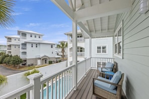 A covered porch with a view of multi-story buildings, a pool, and outdoor furniture. - 2 Beach Homes | Private Pool | Walk to Beach (Panama City Beach)