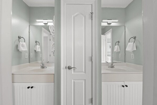 Un baño con dos lavamanos, una puerta y un espejo.