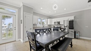 A modern kitchen with white cabinets, a dining table with chairs, a built-in oven, and a stainless steel refrigerator. - The Starfish | 1 Block to Beach • Pool Access (Panama City Beach)