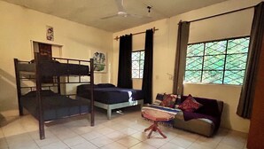 A room with bunk beds, a sofa, a small table, and a window with curtains. - Hostalito Lahar (Bacalar)