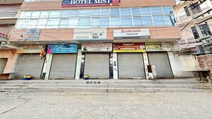 Un edificio de varios pisos con un llamativo letrero 'HOTEL MIST', varias tiendas y fachada de ladrillo.