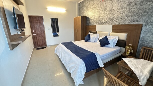 Un dormitorio con cama, cabecera de madera, mesita de noche y televisor en la pared.