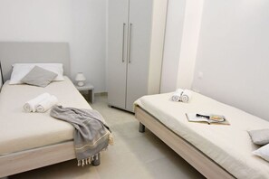 Een slaapkamer met twee bedden, een garderobe, een nachtkastje en een lamp.
