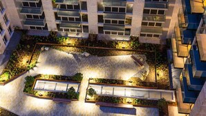 Um edifício alto com várias varandas, um jardim no terraço com áreas de estar e uma piscina.
