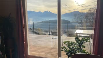 Une pièce dotée d’une grande porte-fenêtre coulissante donnant sur un balcon avec vue sur les montagnes.