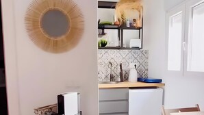 Et moderne køkken med et hvidt køleskab, en sort hylde med et hvidt håndklæde, og et spiseområde med et bord og stole.