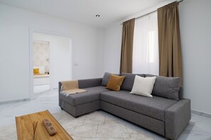 A modern living room with a grey sectional sofa, a wooden coffee table, and a remote control. - Villa Aurora (Ponta Delgada)