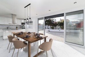 A modern kitchen with a dining area, large windows, and a view of the outdoors. - Villa Aurora (Ponta Delgada)
