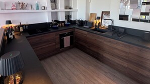 Ett modernt kök med träskåp, en inbyggd ugn och en stor köksö med en diskho.