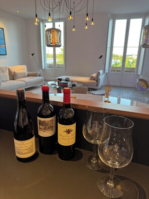 Ein modernes Wohnzimmer mit einer Weinbar, darunter drei Weinflaschen und zwei Gläser.