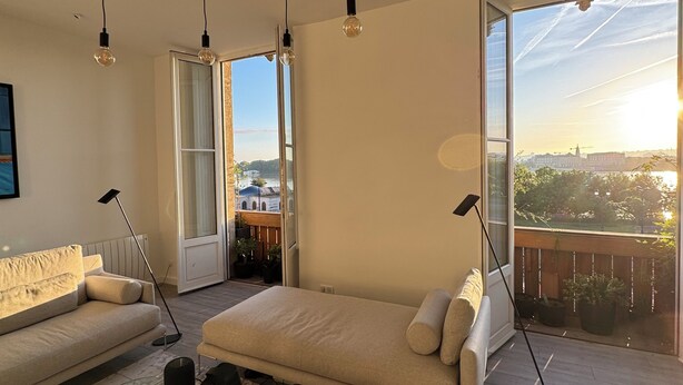 Ett modernt vardagsrum med en soffa, ett soffbord och hängande lampor.