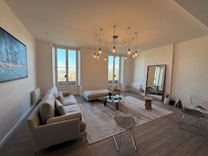Ein geräumiges Wohnzimmer mit einem großen Sofa, einem Couchtisch und einer Chandelier.
