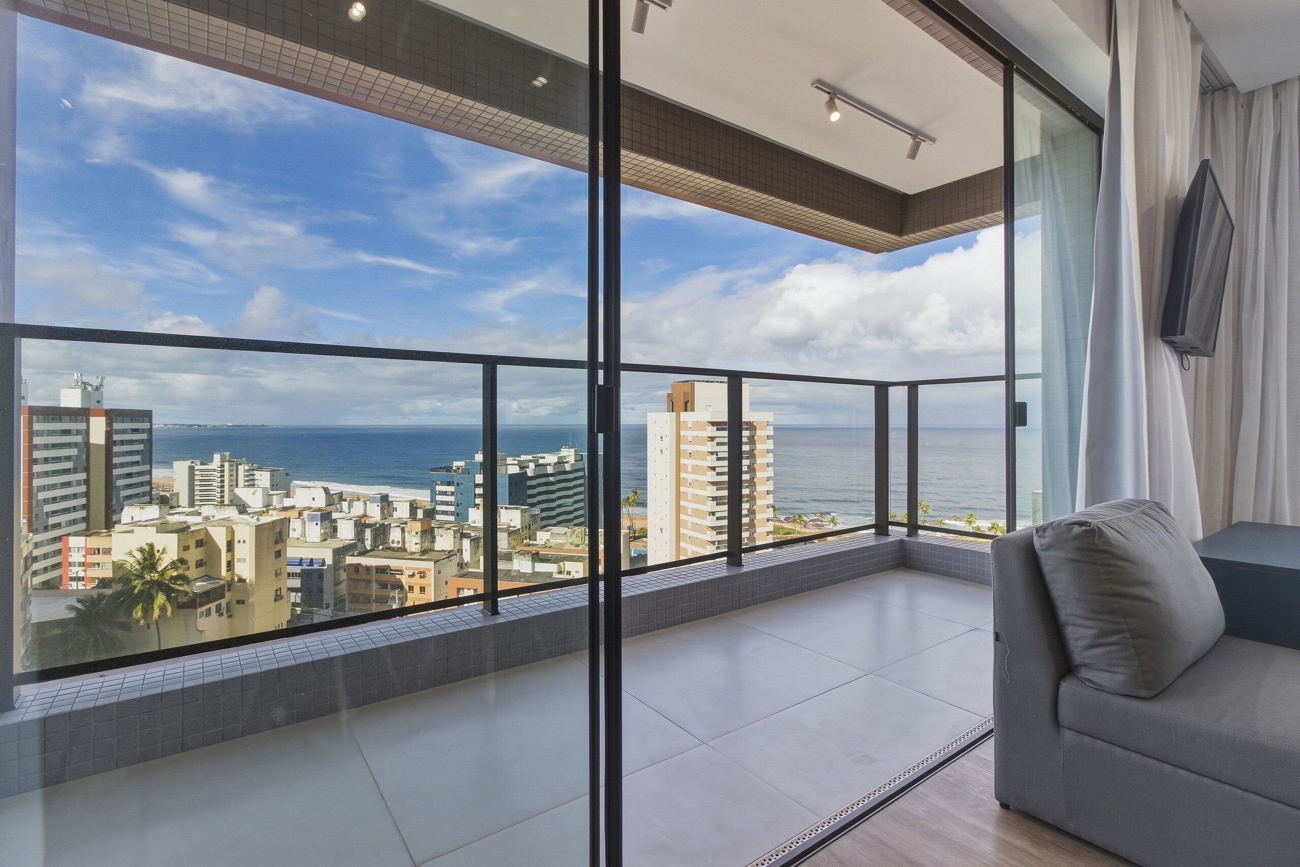 A balcony with a city view, a sofa, and a TV mounted on the wall.