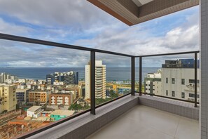 Ein Hochhausapartment mit Balkon und Blick auf Stadt und Meer.