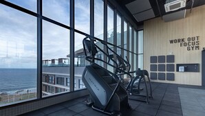 Una palestra con ampie finestre, un tapis roulant e una parete con la scritta 'WORK OUT FOCUS GYM'.