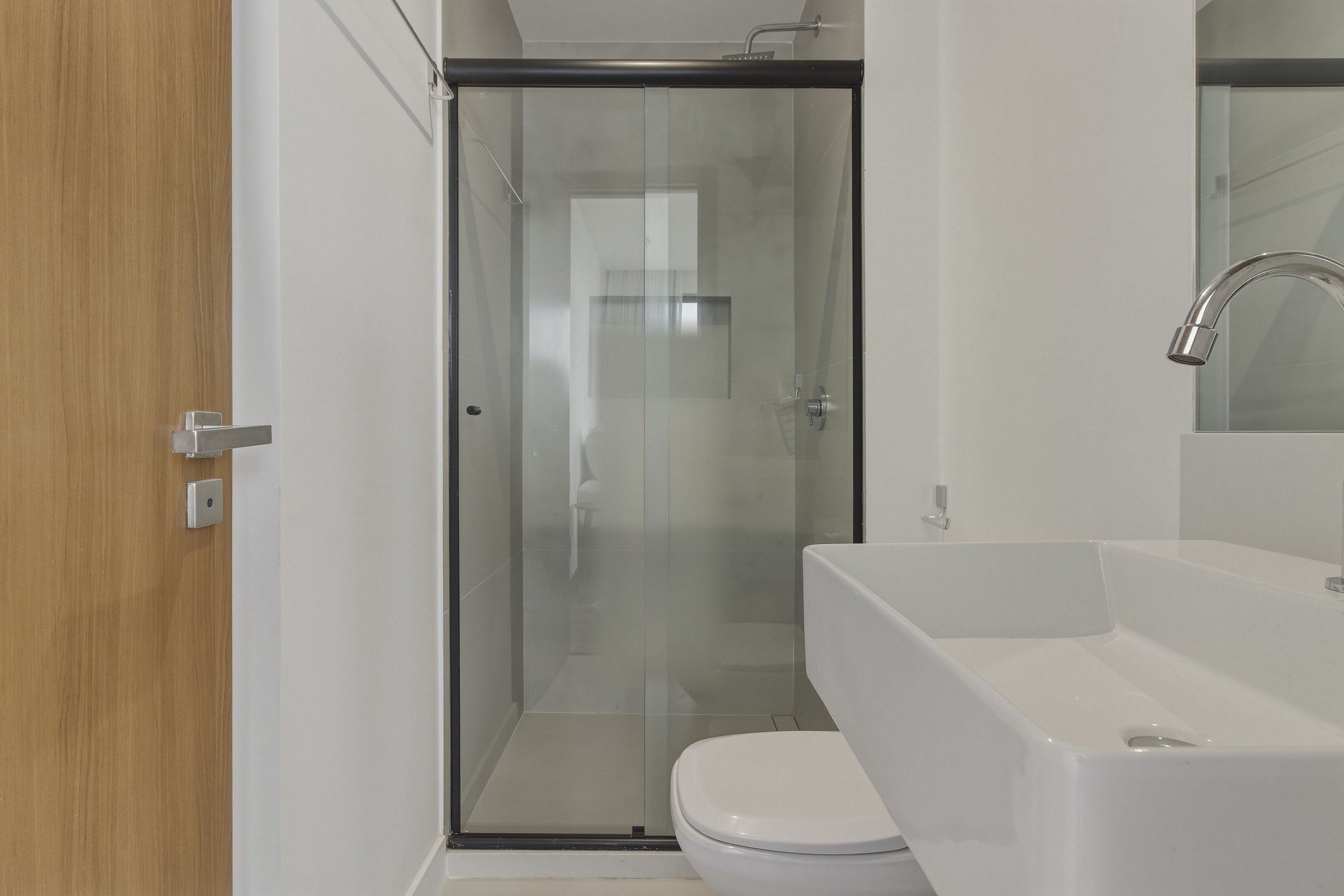 Une salle de bain moderne avec une douche à parois de verre, un lavabo blanc et des toilettes.