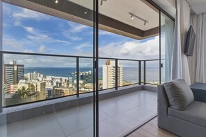 A balcony with a city view, a sofa, and a TV mounted on the wall. - Lit 760 - Close to the Beach and the Convention Center Housi by Carpediem (Salvador)