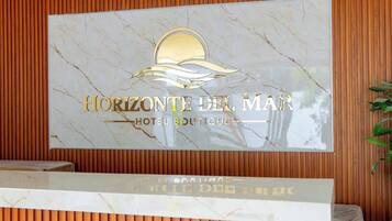 Mostrador de recepción con un cartel que dice 'HORIZONTE DEL MAR HOTEL BOUTIQUE'.