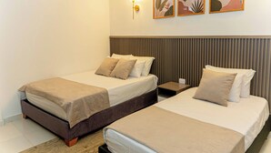 A hotel room with two beds, a nightstand, a lamp, and three framed artworks on the wall. - Horizonte del Mar Hotel Boutique  (Santa Marta)