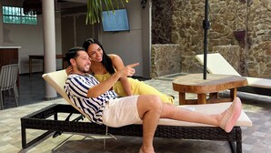 A couple relaxing on a wicker lounge chair under a large umbrella, with a stone wall and a TV in the background. - Horizonte del Mar Hotel Boutique  (Santa Marta)