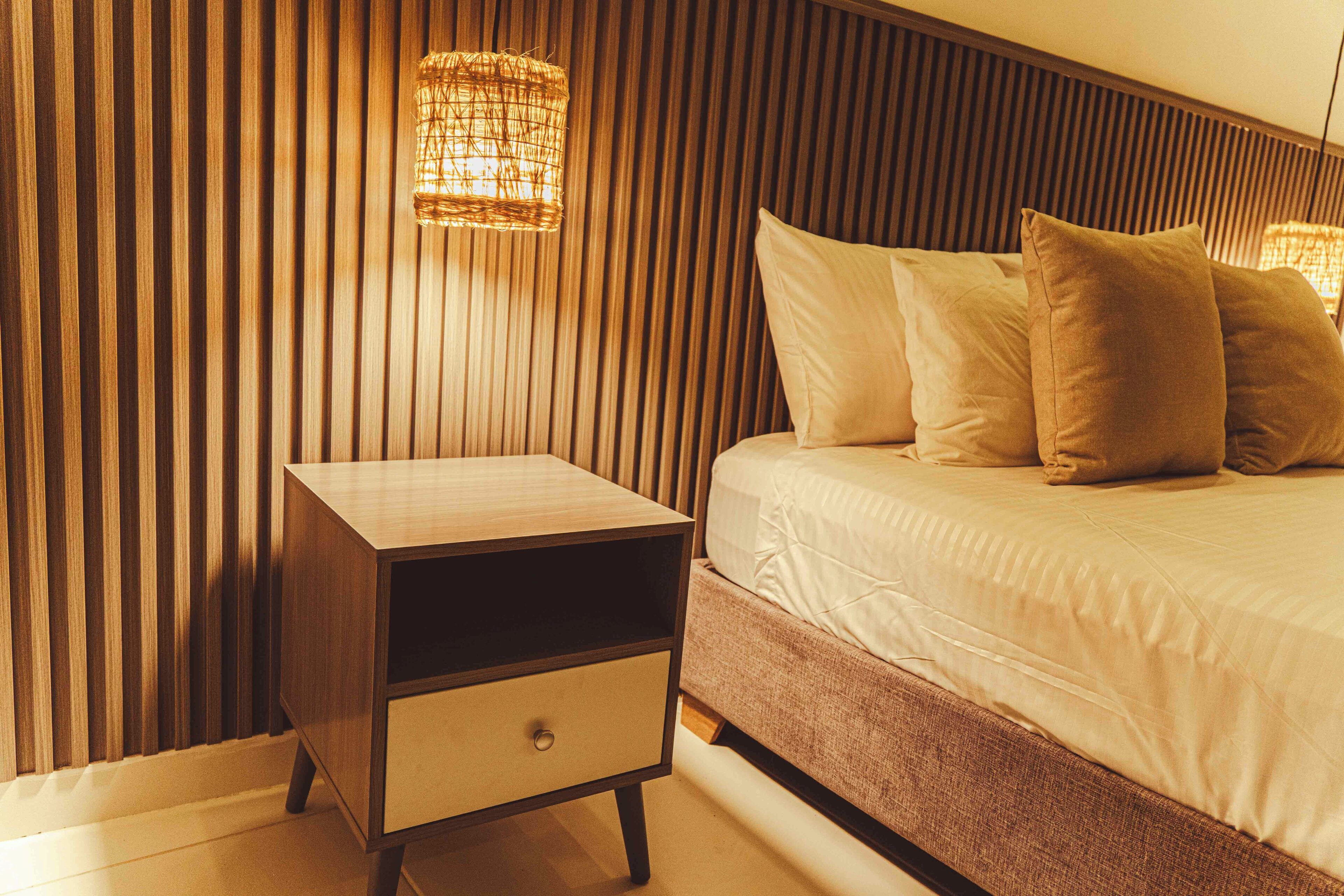 A bedroom with a bed, a nightstand, and a wall-mounted light fixture.