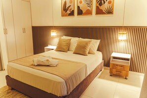 A hotel room with a large bed, bedside tables, a wardrobe, and artwork on the wall. - Horizonte del Mar Hotel Boutique  (Santa Marta)